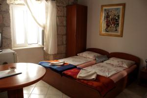 Cama pequeña en habitación con mesa y ventana en Apartment Biline Center, en Korčula