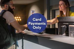a man and woman standing at a counter with the words card payments only at a&o Prague Rhea in Prague