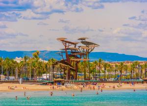a group of people on a beach with a roller coaster at Luxury Beachfront Family Apartment in La Pineda