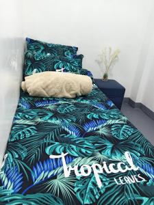 a bed with a tropical themed bedspread with a pillow at Barnwood Homestay in Talap
