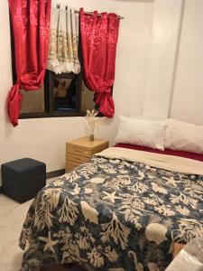 a bedroom with red curtains and a bed at Barnwood Homestay in Talap +2 photos