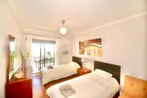 a bedroom with two beds and a balcony at Bay in São Martinho do Porto +24 photos