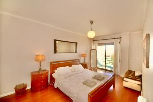 a bedroom with a bed and a chair and a window at Bay in São Martinho do Porto