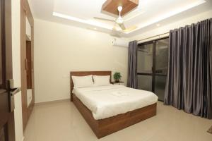 Un dormitorio con una cama y un ventilador de techo. en Laura Airport Suits & Apartments, en Nedumbassery