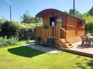 a large wooden cabin with a deck and a table at Roulotte rêve de bohème in Moisson