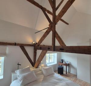 a bedroom with a large white bed with wooden beams at EVERELMUS Boutique Hotel in Bruges