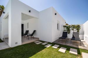 Una habitación con paredes blancas y sillas y césped. en Meraki2-Picina cubierta climatizada, en Novo Sancti Petri