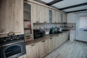 a kitchen with wooden cabinets and a black microwave at Boierița Home Stay in Fundu Moldovei
