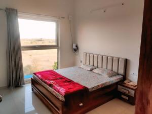 a bedroom with a bed with a large window at Luxurious Apartment in GIFT City in Koba +32 photos