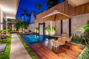 a backyard with a pool and a table and chairs and an umbrella at Arusa Home Bali - Luxury Private Suites Canggu in Canggu
