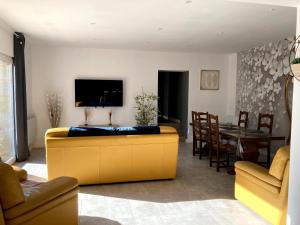 a living room with a yellow couch and a dining room at Les Gites de Pilot in Lussac
