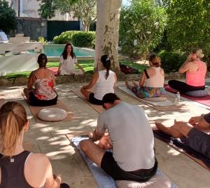 a group of people sitting in a yoga pose by a pool at Maison d'hôtes La Bastide de Patou in Marseille