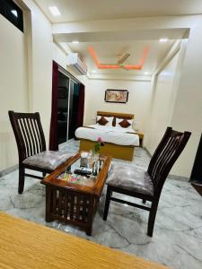 浦那Hotel Fun Suite- Baner Hill的一间卧室，配有一张床、一张桌子和几把椅子