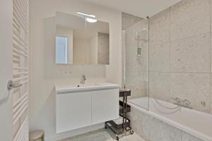 een witte badkamer met een wastafel en een douche bij Boardwalk 11 O4O2 G Ii7 in Nieuwpoort
