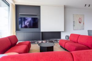 un soggiorno con divani rossi e una TV di Sea meets sky - Ensor a Ostenda