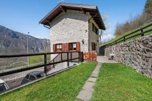 un pequeño edificio de piedra en una colina con una valla en Ca'della Melania, en Folgaria
