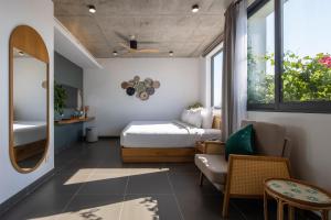 une chambre avec un lit, une chaise et un miroir dans l'établissement Leaf Beachfront Hotel Da Nang, à Đà Nẵng 79 autres photos