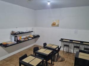 a dining room with tables and chairs and a counter at Avenida Hotel in Presidente Prudente