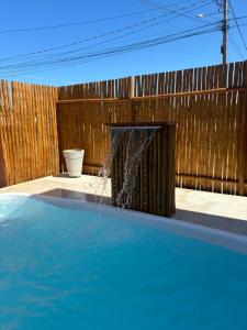 a water fountain in front of a wooden fence at Pousada Solare Home in São Miguel do Gostoso