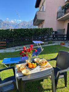 une table avec une assiette de fruits et de fleurs dessus dans l'établissement Casa Sally - Lago e montagna, à Cresciasca