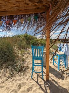 two blue chairs sitting in the sand under a tent at Каравана The Jungle in Chernomorets
