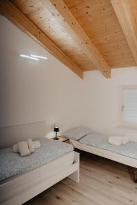 two beds in a room with wooden ceilings at Al Vicolo Holiday Home in Nave San Rocco +35 photos