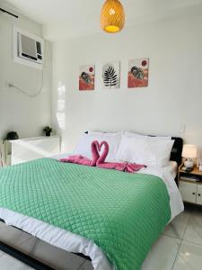 a bed with a green comforter with two pink bows at Aizen's haven at Casa Mira Guadalupe in Cebu City