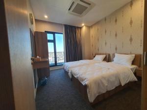 een hotelkamer met twee bedden en een raam bij Royal Bakrajo Hotel in As Sulaymānīyah