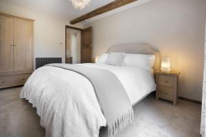 a bedroom with a white bed and a wooden cabinet at Riverside - Quaint County Cottage overlooking the Beck in Caldbeck
