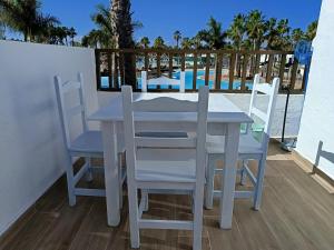 a white table and chairs on a balcony with a pool at Oasis Duna - Casa Mariposa in Corralejo