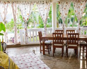 Un comedor con mesa y sillas y ventanas. en Swahili house, en Galu