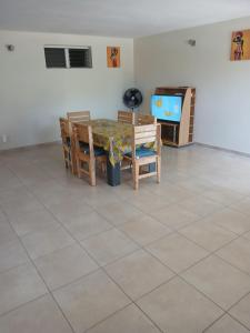ein Esszimmer mit Tisch und Stühlen und einem Fernseher in der Unterkunft Maloubière locations in Les Anses-dʼArlets