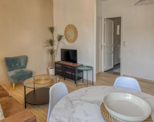 a living room with a table and chairs and a television at le harley haven in Compiègne