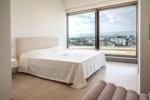 チヴィタノーヴァ・マルケにあるTra sole e luna - Civitanova, appartamento nobiliare fronte mareの大きな窓のある部屋にある白いベッド