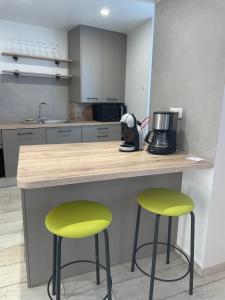 a kitchen with two green bar stools at a counter at Maison Marguerite in Chouilly +20 photos