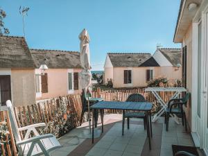 Un patio con mesa y sillas y una valla. en VVF Golfe du Morbihan Sarzeau Arzon, en Sarzeau