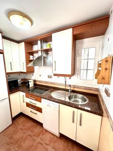 a kitchen with white cabinets and a sink at Apartamento a pie de playa en El Portil in El Portil