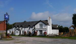 a white building with a clock tower in front of it at Garway Moon Inn in Garway