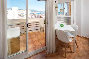 Una pequeña mesa blanca y sillas en una habitación con balcón. en Plazamar 039, en Torre del Mar
