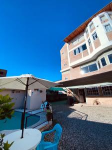 a table with an umbrella next to a building at Hotel Altas Cumbres in Villa Carlos Paz