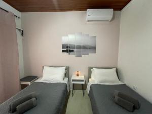 een kamer met 2 bedden en een tafel met een lamp bij Dada's Cottage in Argyrádes