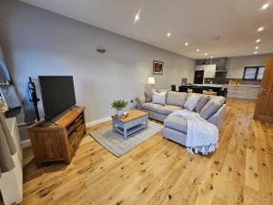 a living room with a couch and a flat screen tv at Lakefront Lodge with Hot Tub - Aylesbury Lodge in Shepton Mallet