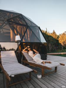 a woman laying on a bench on a deck at KUUL STAY - luxury domes in Virtsu