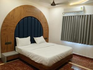 a bedroom with a large bed with a blue headboard at Dwarka Dekho - Grand Palace in Dwarka