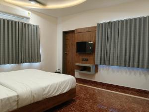 a bedroom with a bed and a flat screen tv at Dwarka Dekho - Grand Palace in Dwarka