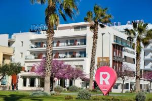un edificio blanco con palmeras y una señal rosa en Hotel Marina, en Roses