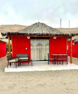 a red building with tables and chairs in front of it at Bungalows en playa Wakama in San Vicente de Cañete