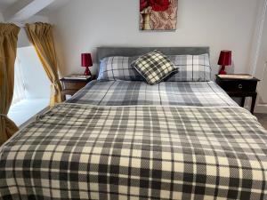 a bed with a checkered blanket and pillows on it at 3 Telford Mews in Dumfries