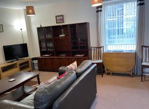 a living room with a leather couch and a television at 3 Telford Mews in Dumfries +7 photos