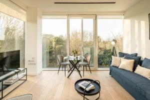 a living room with a blue couch and a table at Chiswick Parkside Apartments by Sleepy Lodge London in Kew Bridge +45 photos